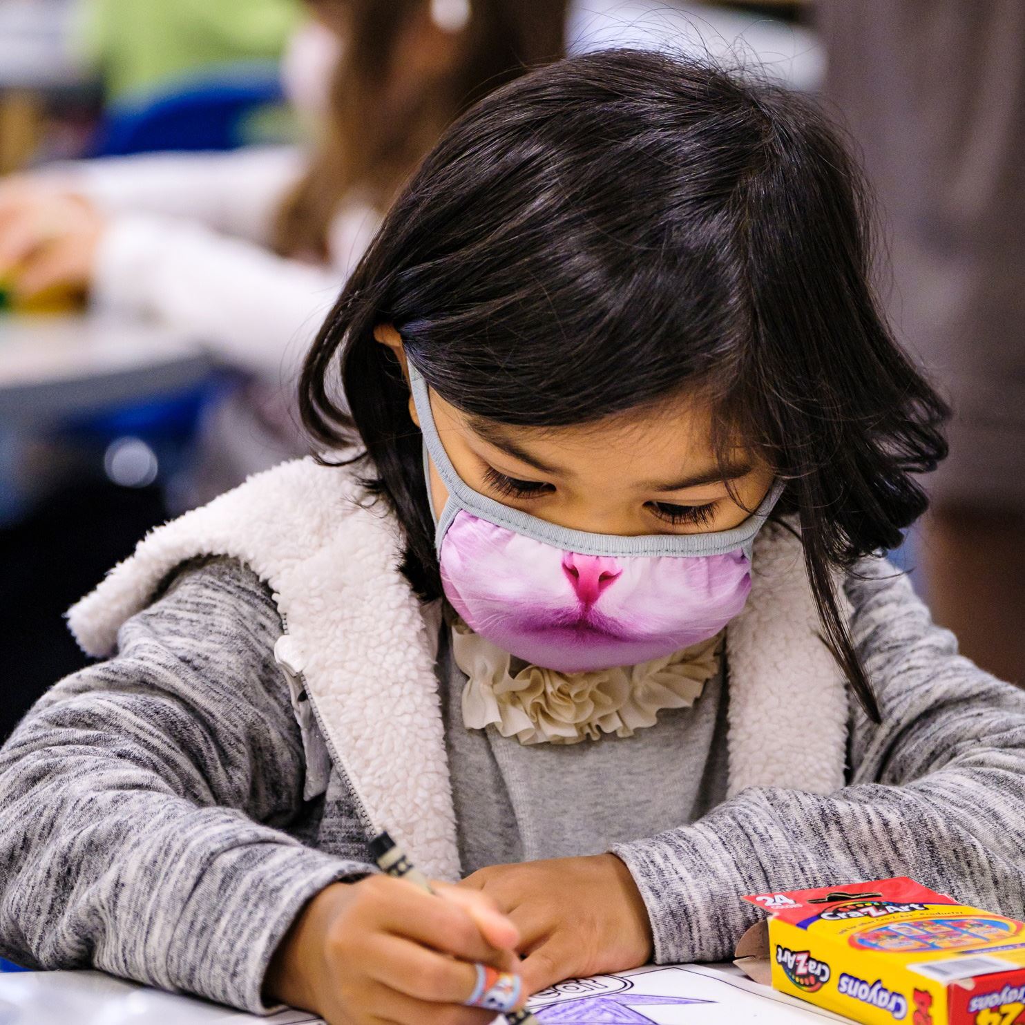  student wearing a face covering and coloring